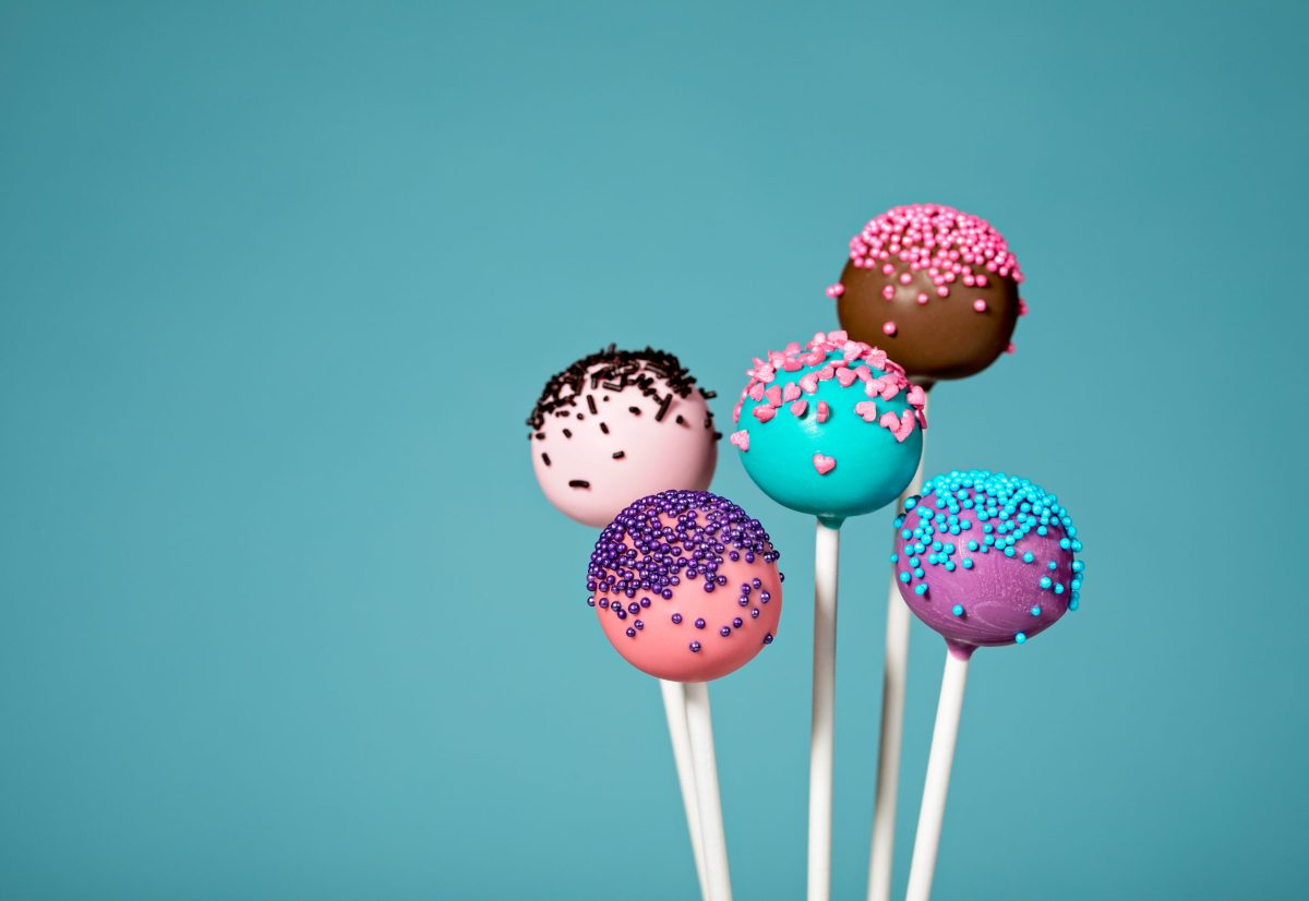 Colorful cake pops with sprinkles over a teal blue background.